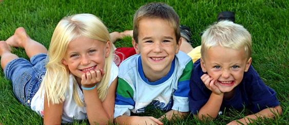 three kids lying in grass